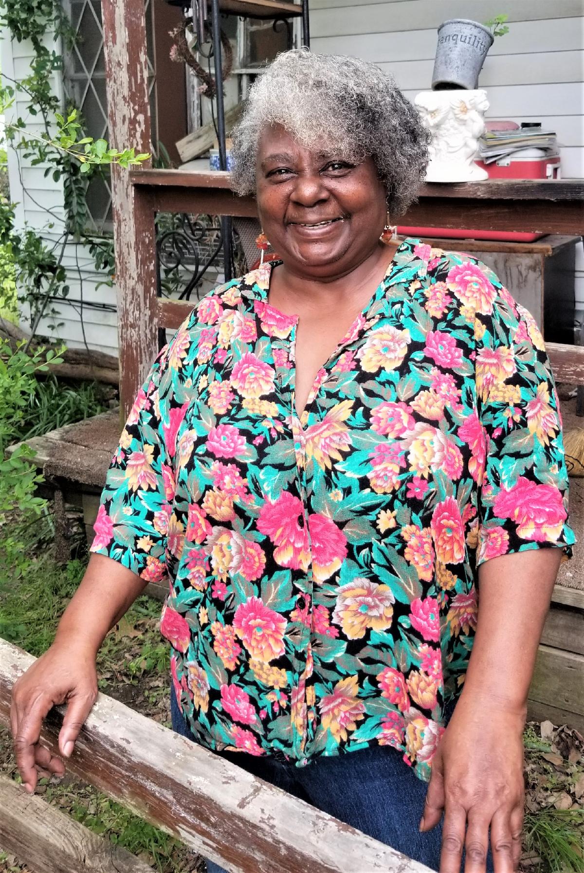 Habitat homeowner smiling, while standing in front of her  newly repaired home