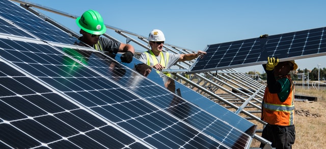 Workers install new solar panels to generate zero emission electricity.