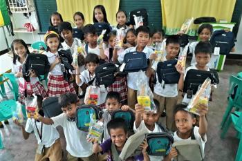 Students at a grade school in Guimba, Philippines happily display their newly received school supplies.