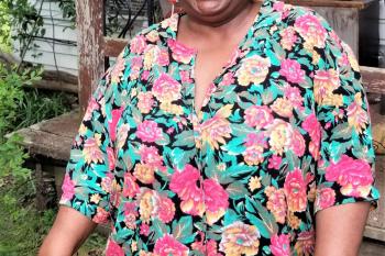 Habitat homeowner smiling, while standing in front of her  newly repaired home