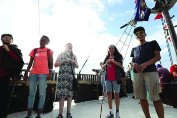 Five blind students with long white canes explore a pirate ship